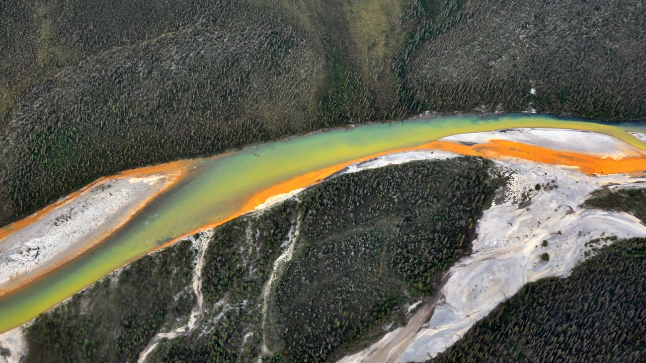 Aerial view of a braided river. One braid entering the main channel is a bright, solid orange.
