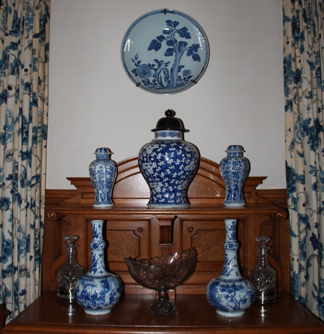 In the Mansion’s dining room is a display of Blue-and-White assorted vases and jars with a charger above