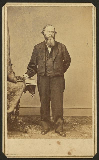 sepia photo of bearded man in suit standing