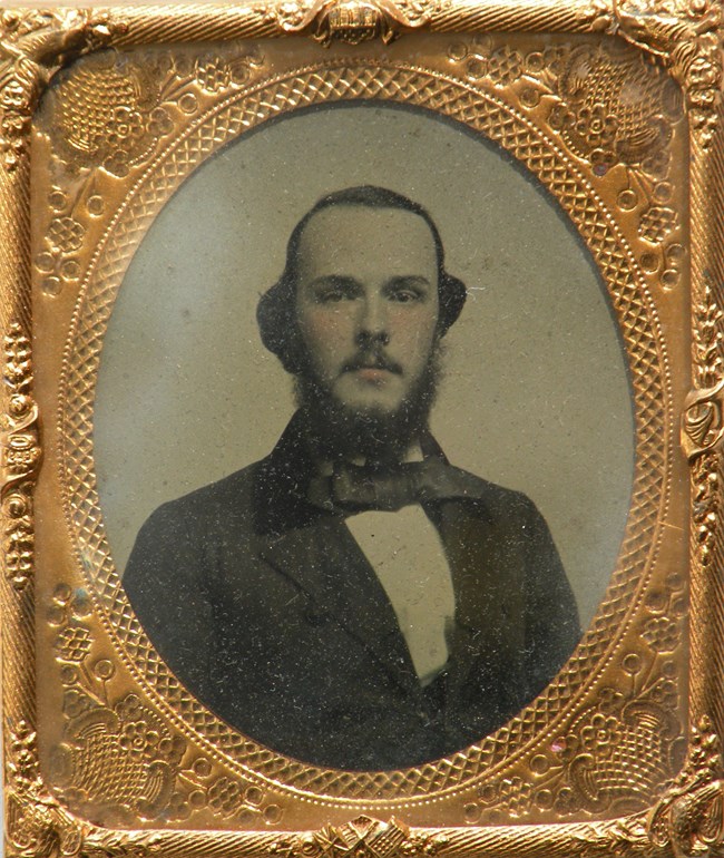 A gold framed black and white image of a man with a suit.
