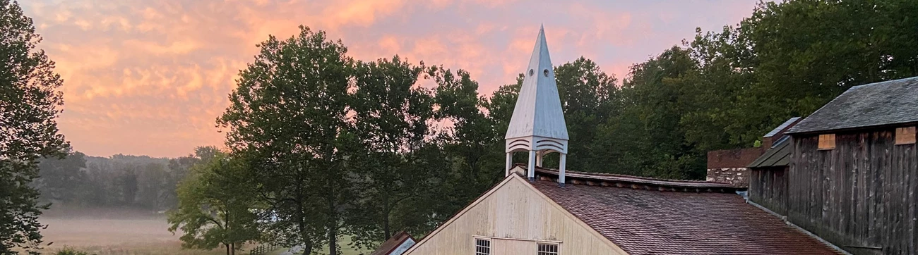 A large white building with wooden roof and white steeple at the top.
