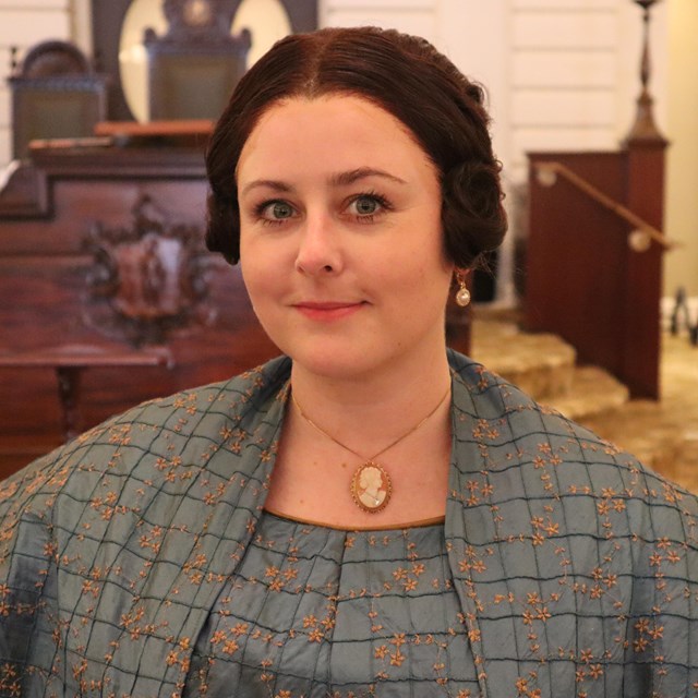 portrait of a woman with parted hair wearing a patterned dress and shawl.