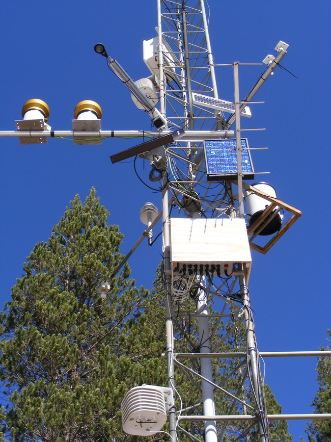 View looking upward at the metal tower and instruments of a weather monitoring station.