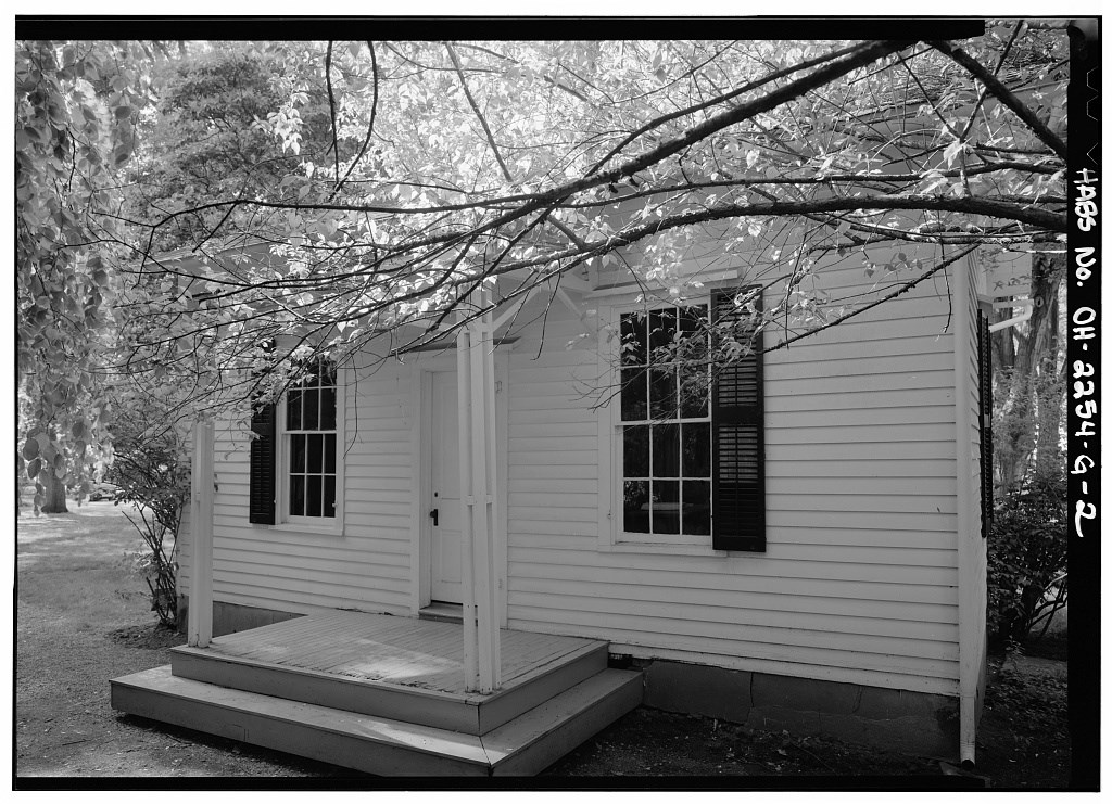 A small single-storey building with a two-pillared porch and shuttered windows