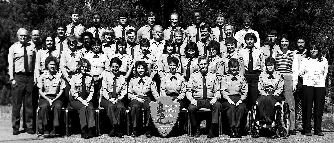 NPS employees pose for a group photo. Most wear NPS uniforms but a few are in street clothes. Erin Broadbent is in her wheelchair in the front row.