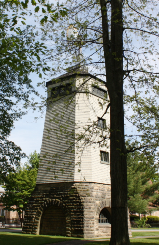 The rebuilt windmill: a tall structure on a stone base with arched openings, among trees