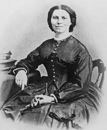 Black and white photo showing woman seated at desk from the 1880s