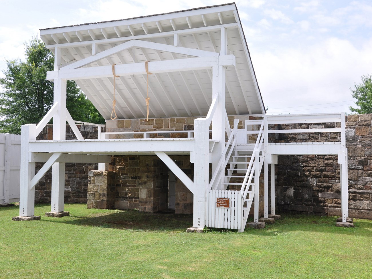 Rope nooses hang from the crossbeam above a platform on the gallows.