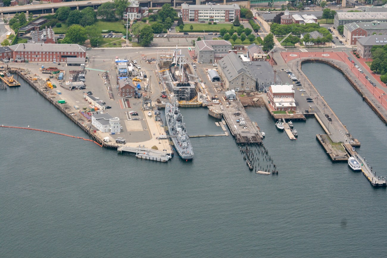 Aerial view of the Charlestown Navy Yard with USS CASSIN YOUNG docked on a pier.