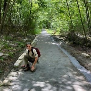 A young woman completes trail work while wearing an AmeriCorps shirt.