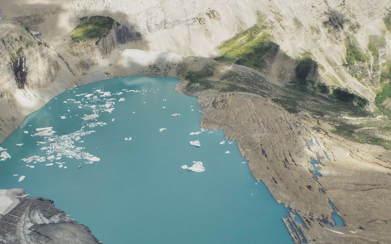 A grainy historic color photo of Grinnell Glacier from high above.