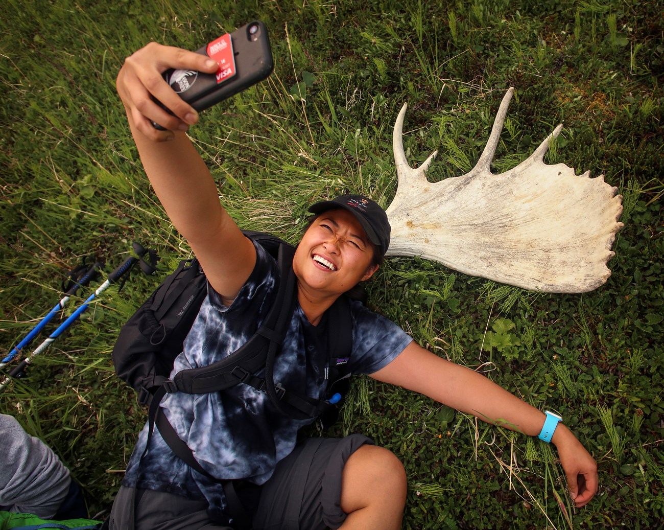 a hiker takes a selfie on the ground with a shed moose antler