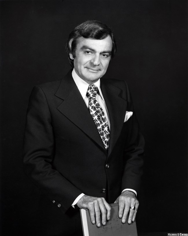 Man in a suit posing with a book