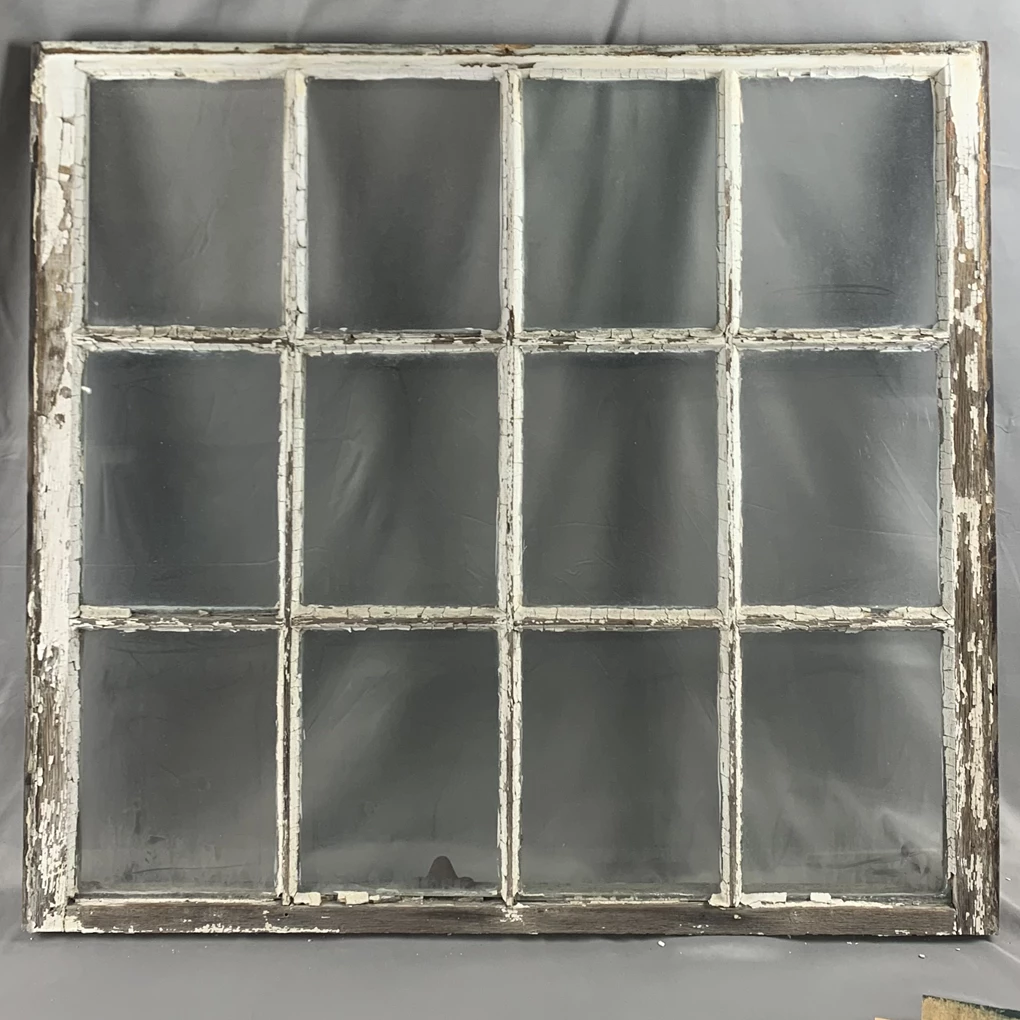 Window with all the paint either chipping off or entirely missing. The visible wood is weathered and grey. The glass panes are four horizontal by three vertical.