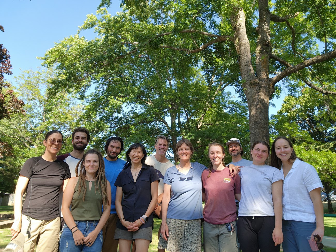 Several smiling people gather for a photo during a picnic.