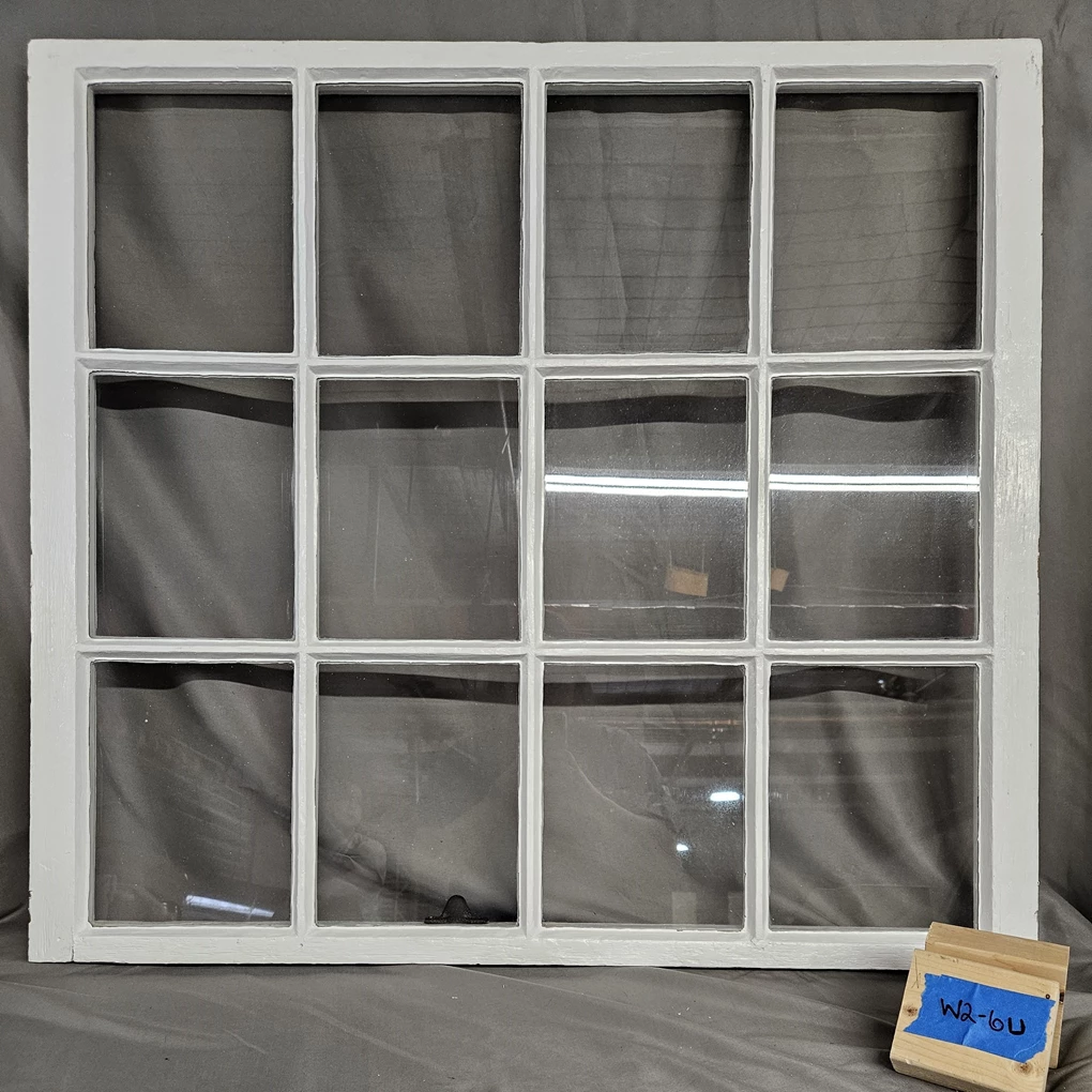 Window with all the paint either chipping off or entirely missing. The visible wood is weathered and grey. The glass panes are four horizontal by three vertical.