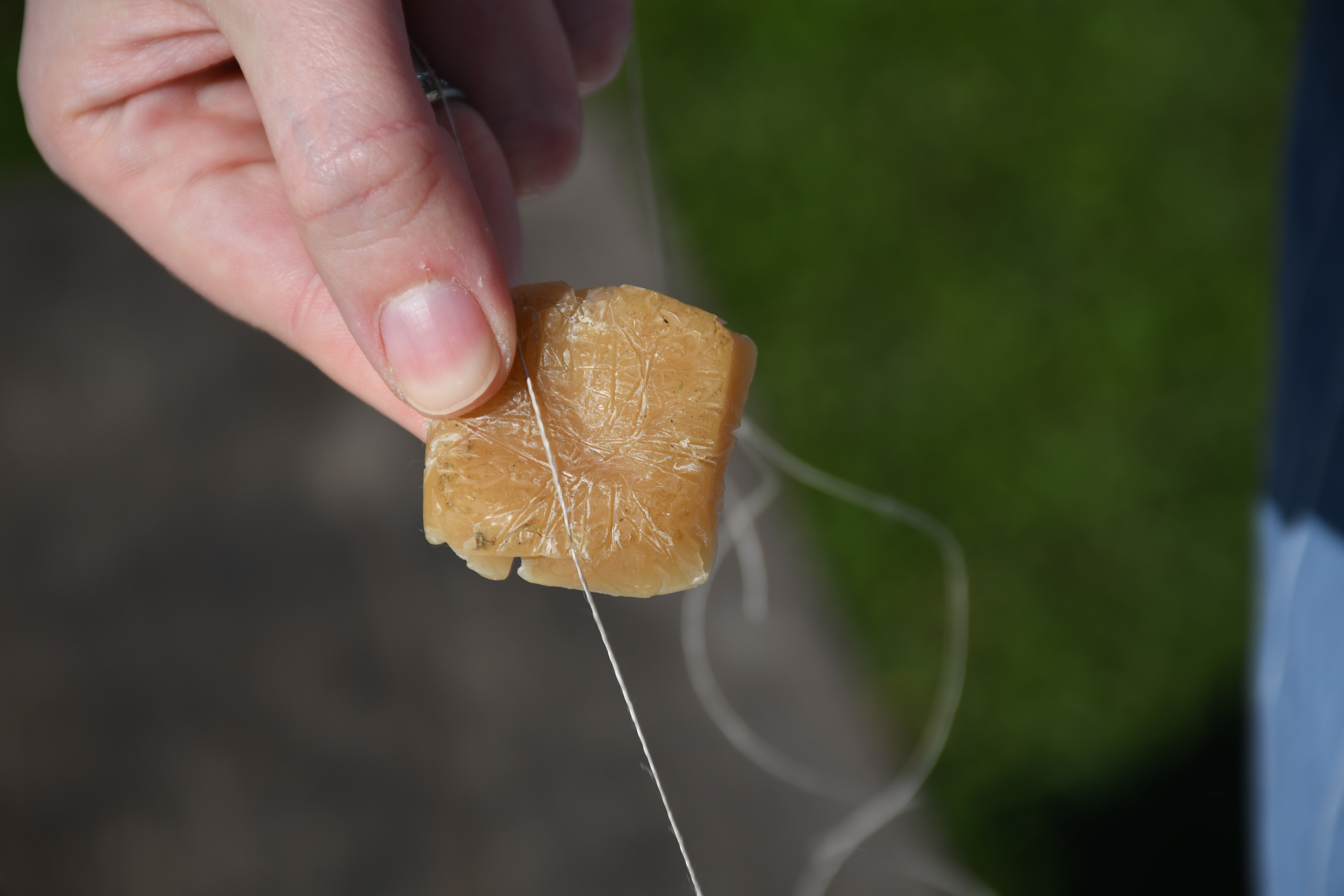 photograph, outdoors, closeup of beeswax and thread