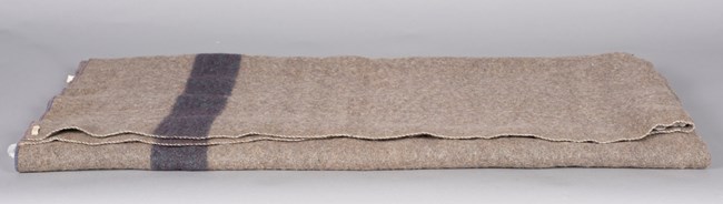 Folded gray blanket with a blue stripe