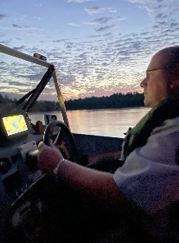 Photograph of person driving boat.