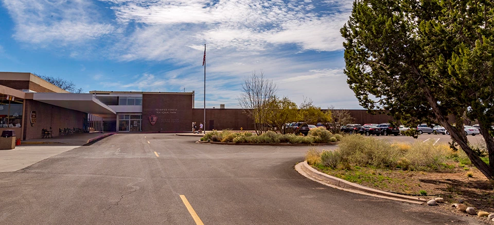 Painted Desert Community Complex is a low, ell-shaped modern style building frames a large parking lot, with several planting islands.