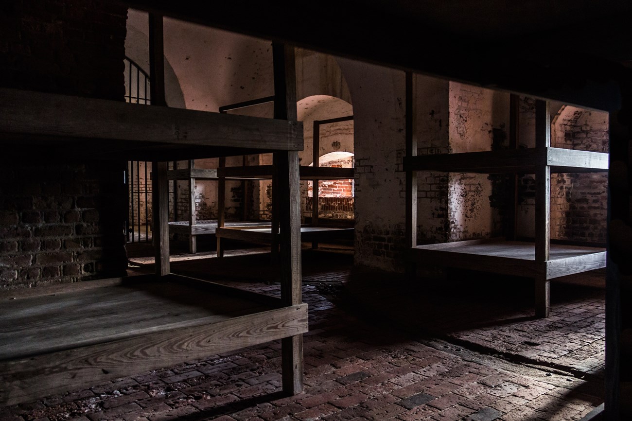 A brick room with several large wooden bunk beds.