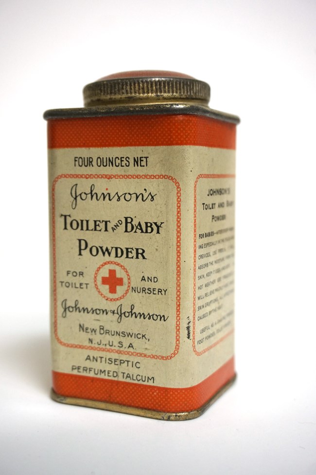 A small rectangular tin of baby powder. The label is red and white. A circular screw top lid sits atop the canister.