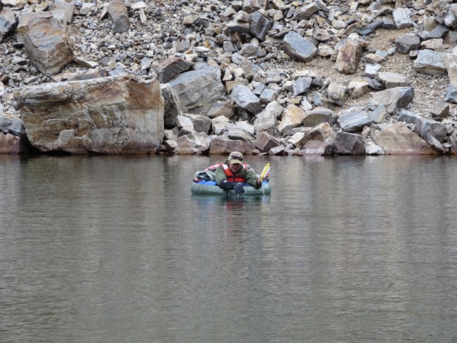Scientist in float tube collects depth measurements in a lake.