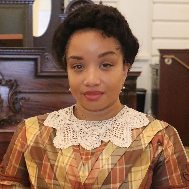 portrait of a black woman with her hair up and wearing a dress with a lace collar.