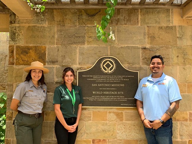 Three people standing next to a sign