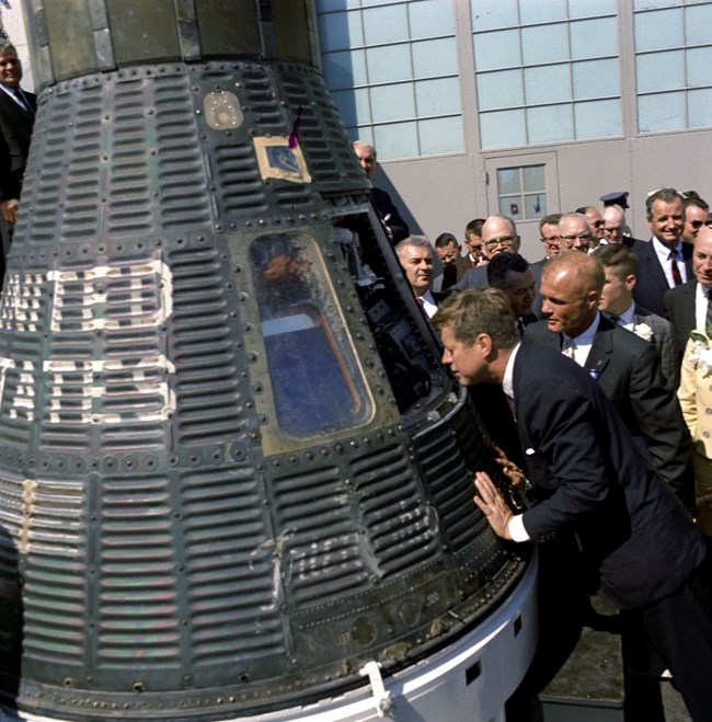 JFK and John Glenn look into a space capsule