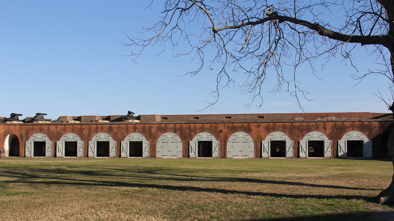 A brick fort with large white rounded top doors along the wall.