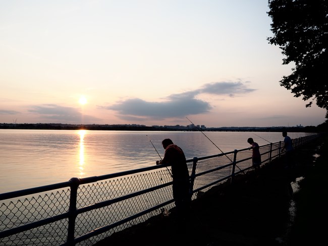 Fishers in silhouette along the Potomac as the sun begins to set.